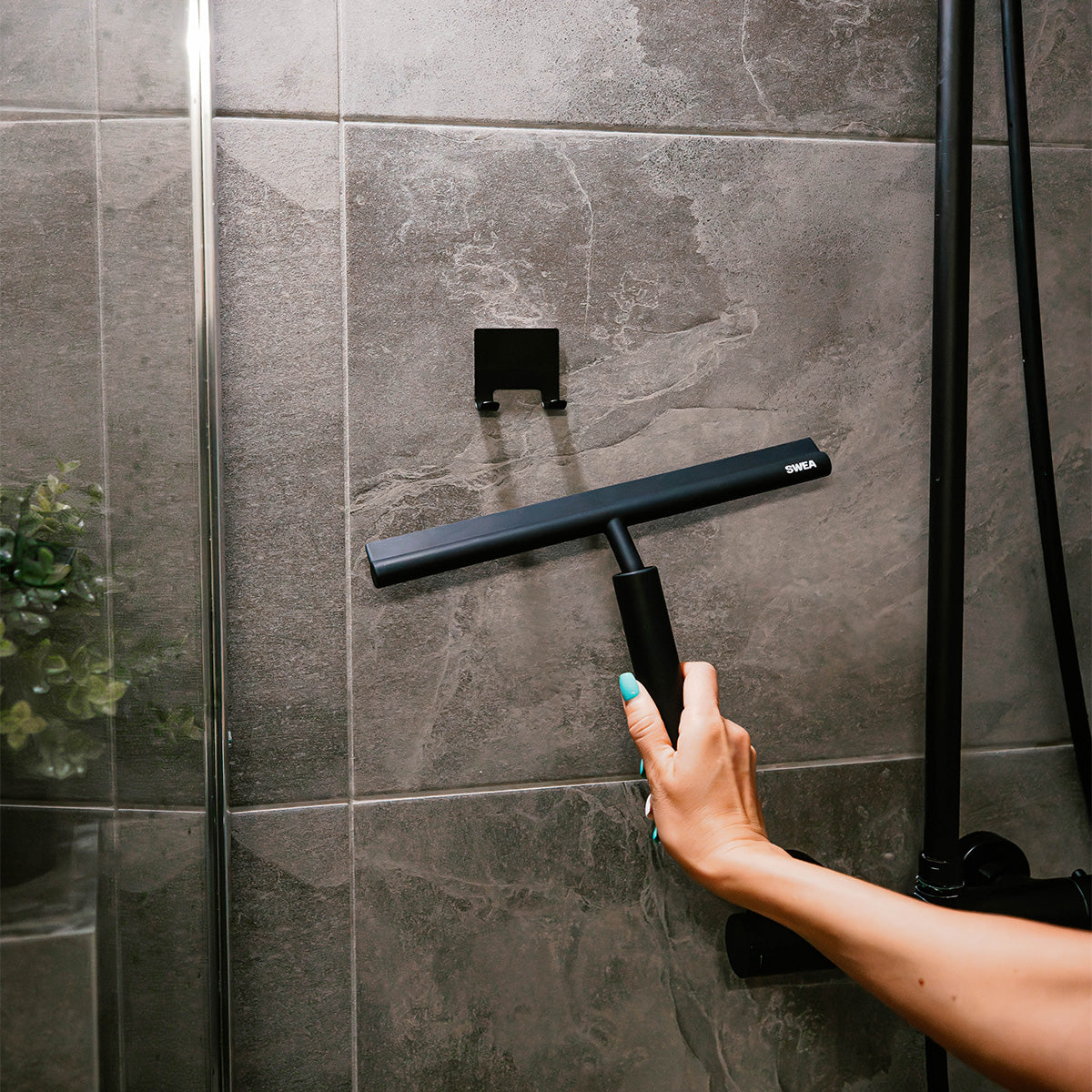 Holding the SWEA shower squeegee in a modern bathroom setting